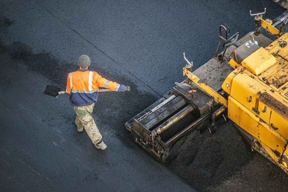 Asphalt contractor laying a protective sealcoat on pavement to protect the asphalt surface before damage spreads