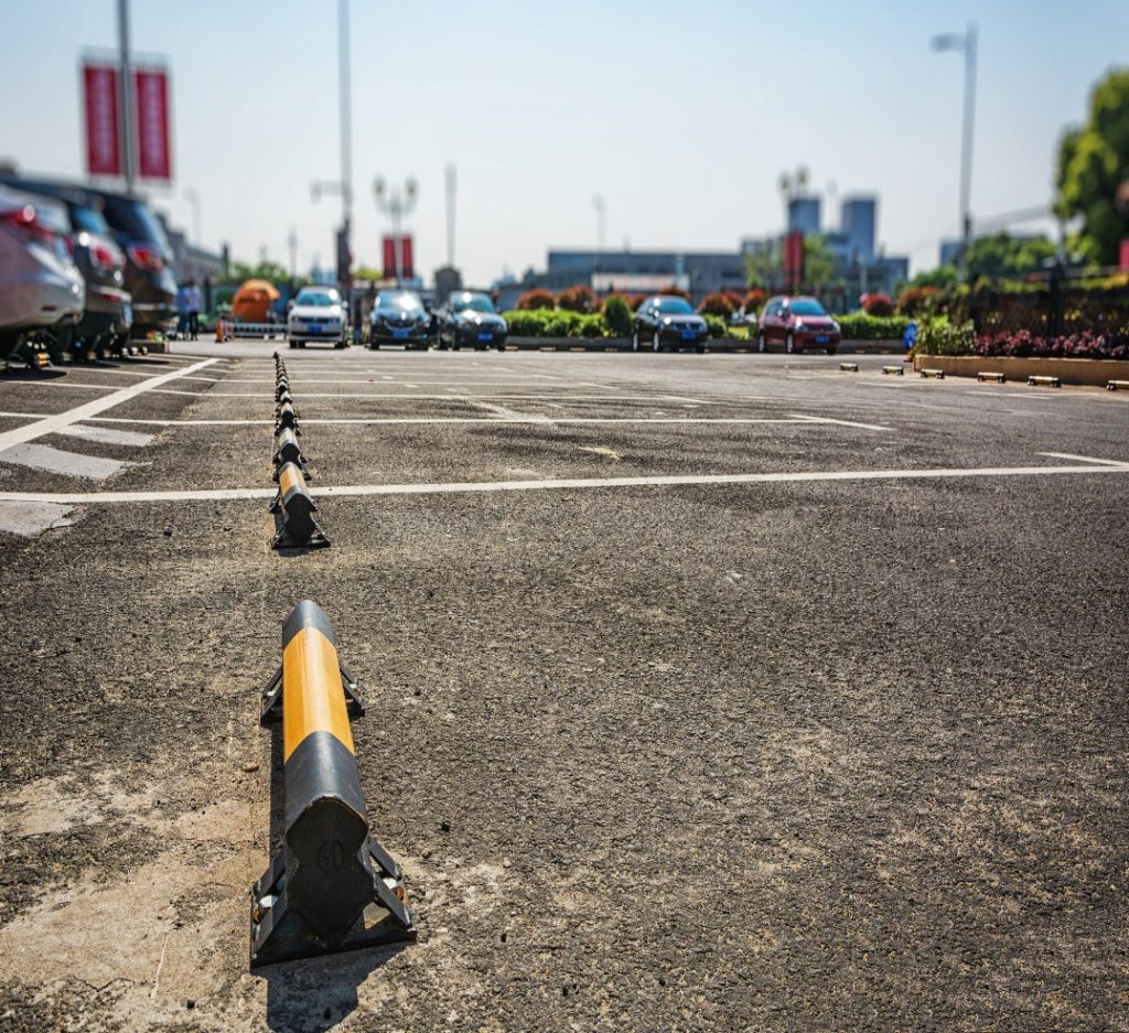 Outdoor parking lot featuring multiple wheel stops aligned across marked parking bays.