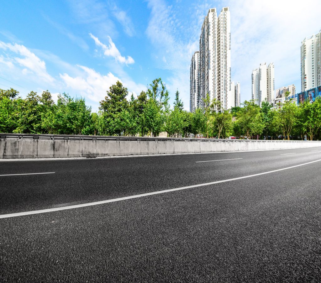 A moving view of an asphalt road leading through a modern city with blurred buildings.