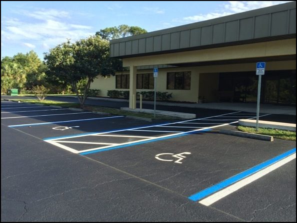 Parking lot freshly sealcoated with wheel stops and clear signage