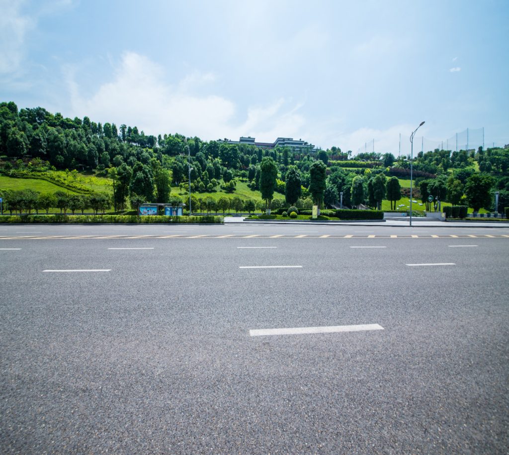 Asphalt road running through a forested area with trees on both sides.