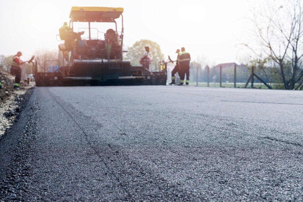 Workers are applying new asphalt coating to repair road cracks and restore the surface