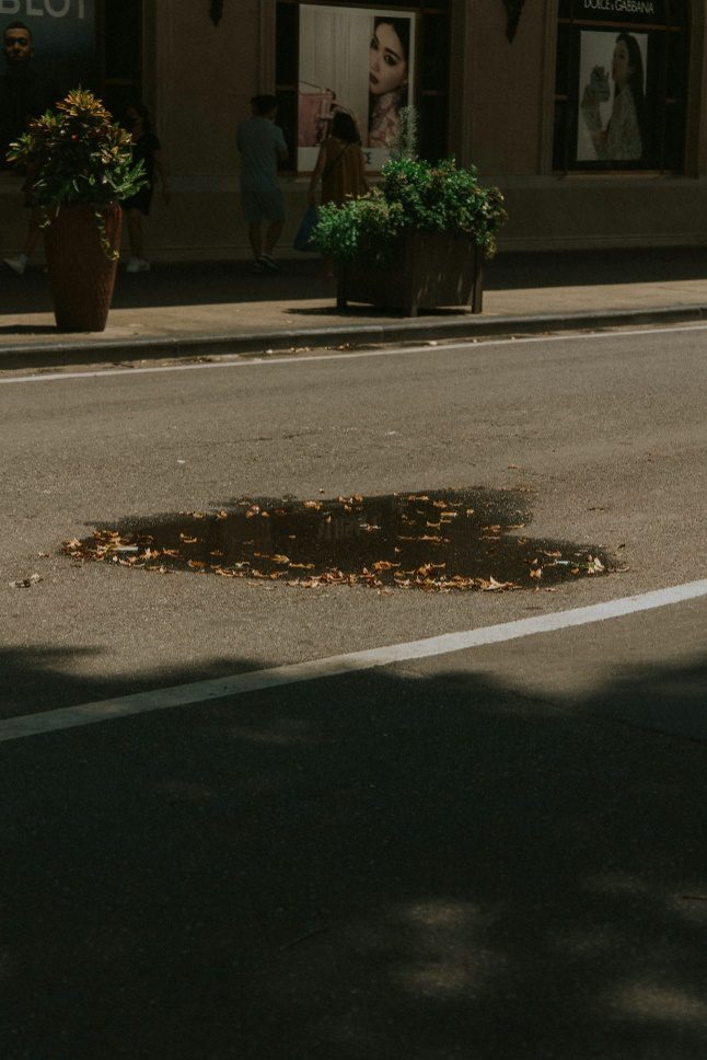A large potholeis forming on a road due to cracks that worsened because sealcoating was skipped