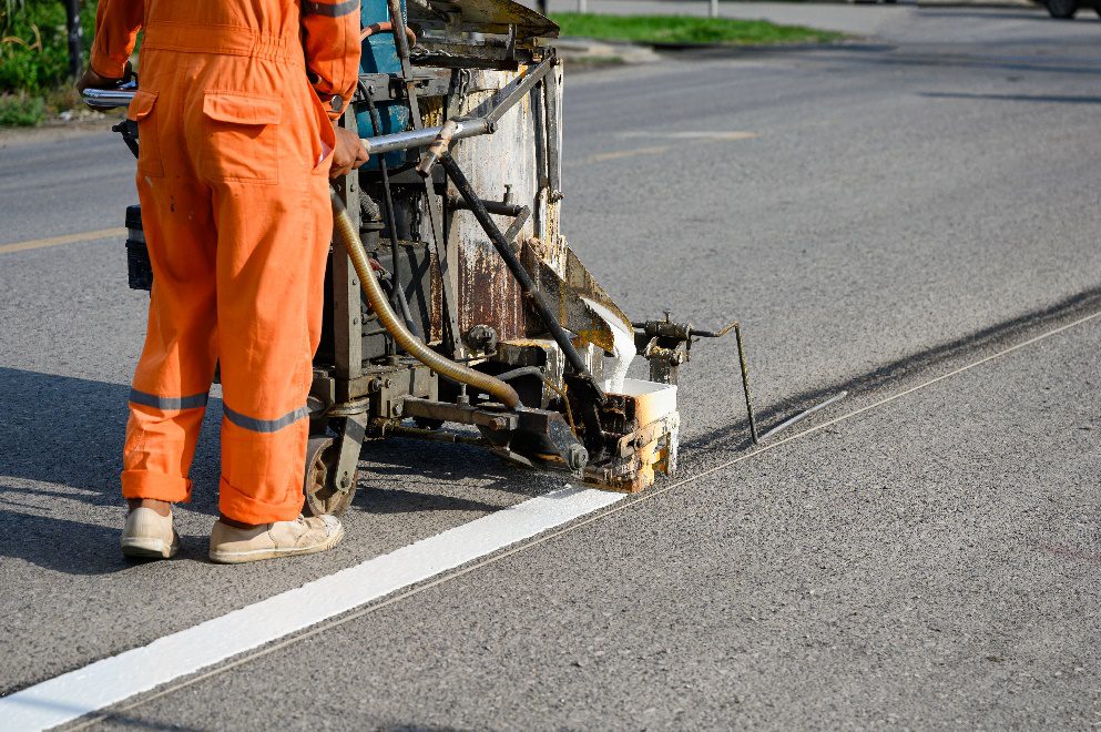 Asphalt contractor painting clear thermoplastic lines on a road surface