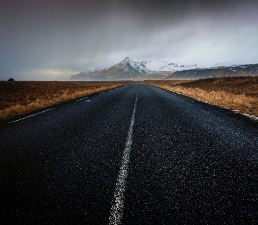 A surface-level view of a newly finished asphalt road stretching toward the horizon.