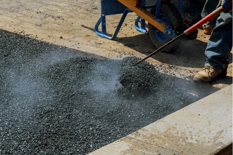 A professional worker applying asphalt sealcoating during maintenance.