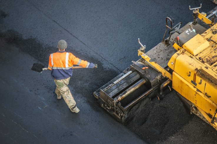 An asphalt expert using a sealcoating machine for driveway maintenance.