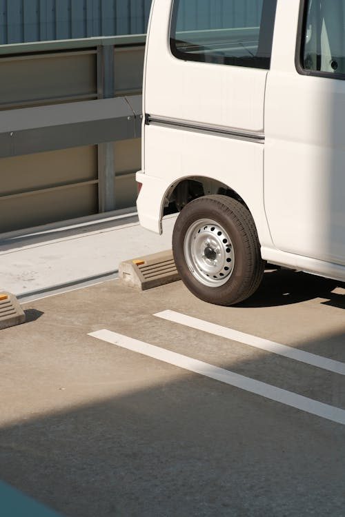 A parked car positioned in front of a wheel stop in a commercial parking lot.