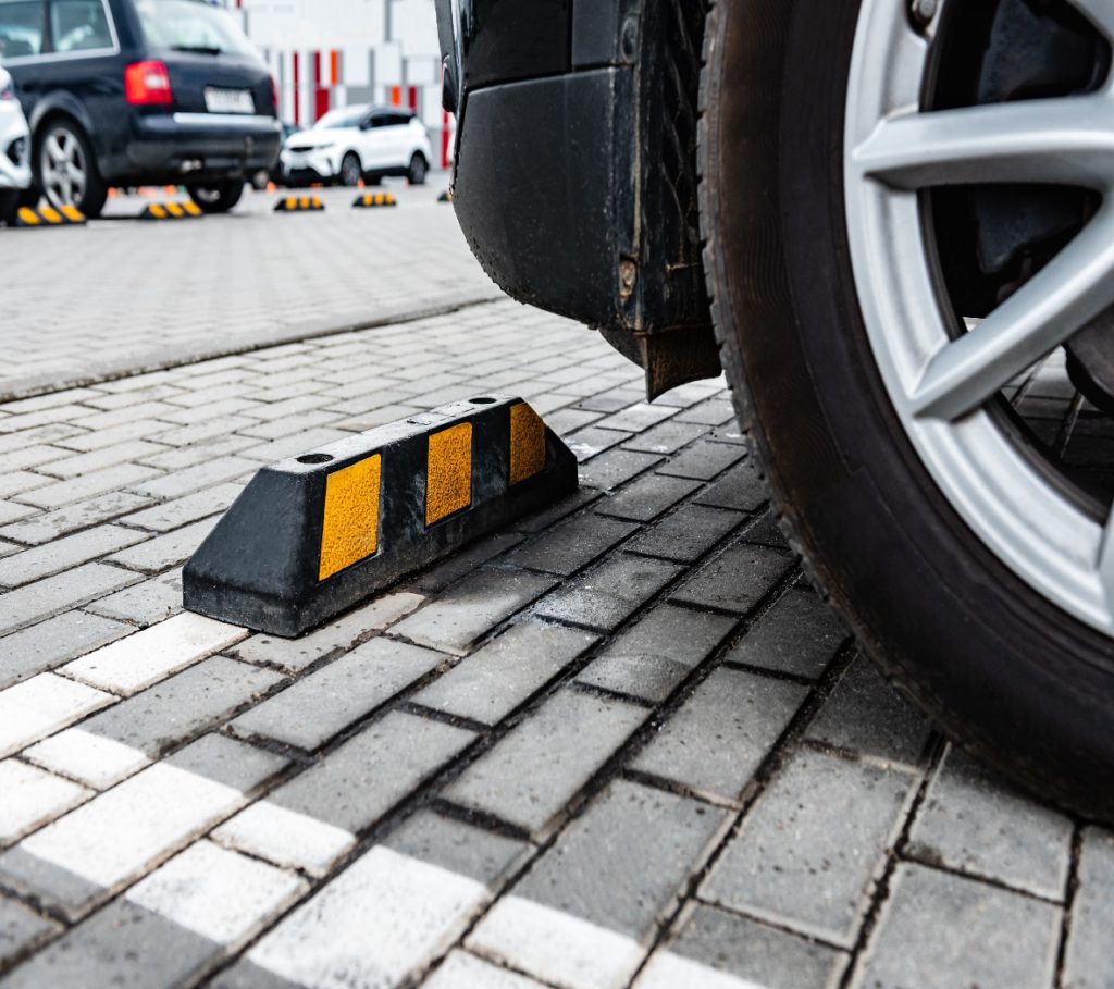 Rubber wheel stops with yellow stripes installed across an outdoor parking lot.