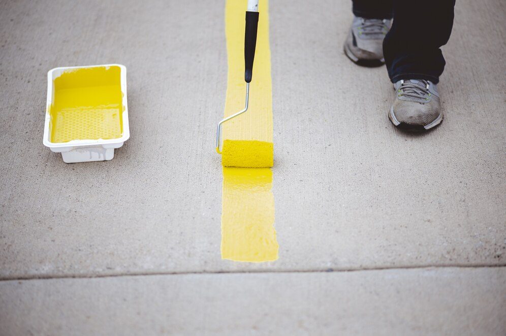 Person repainting parking lines on an asphalt parking lot in Englewood
