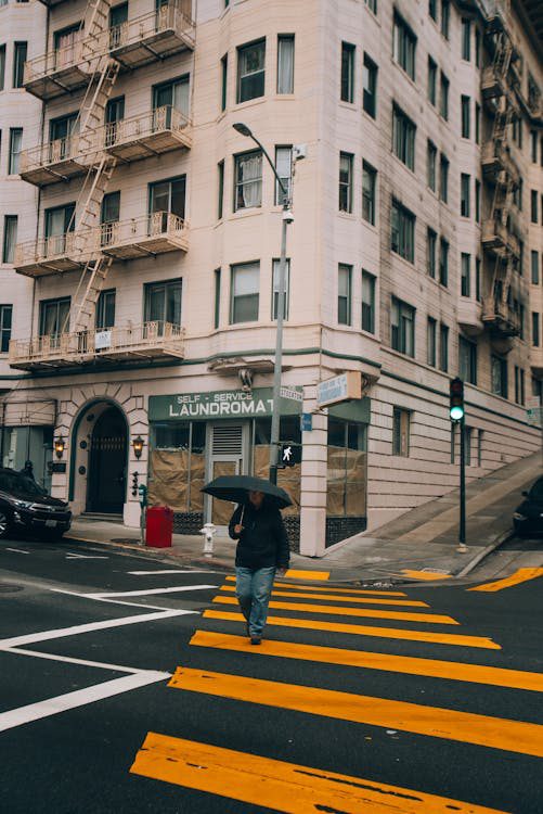 person walking across a street with an umbrella