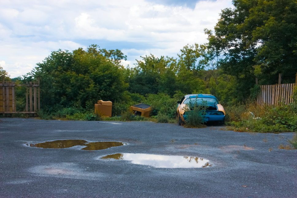 Potholes filled with water in a neglected parking lot, creating safety hazards for drivers and pedestrians