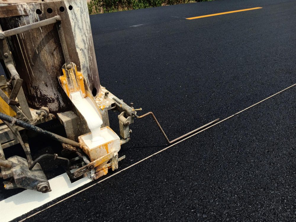 Machine applying fresh striping on asphalt pavement to improve layout accuracy