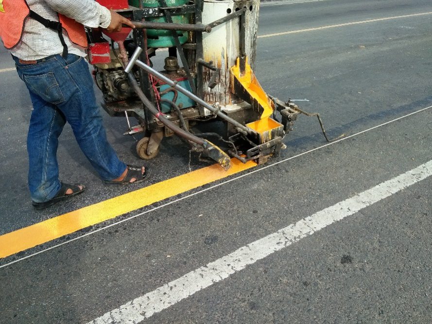 A road worker applying thermoplastic striping that provides durable, long-term pavement markings